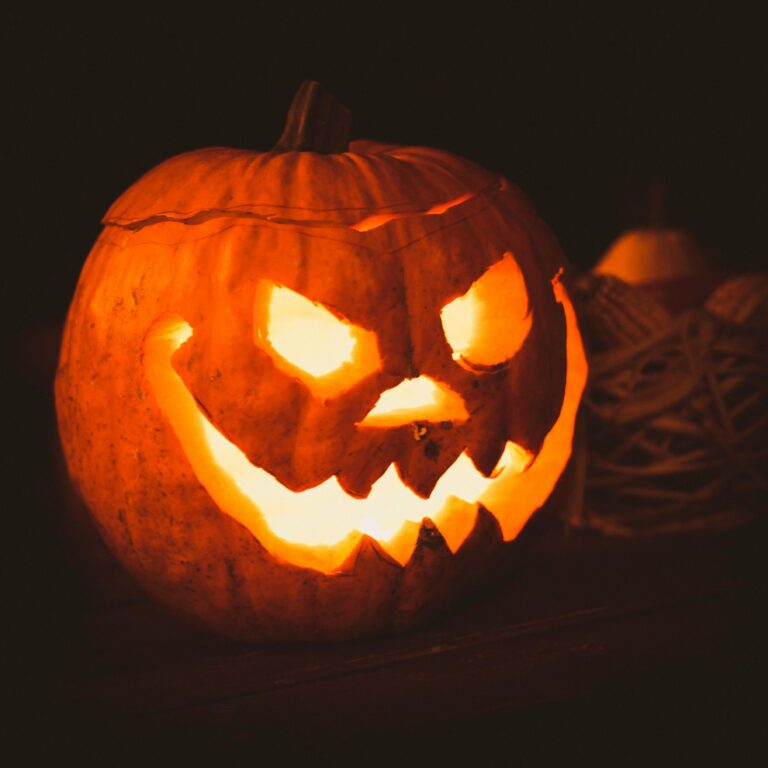 A carved pumpkin with a creepy face illuminated for Halloween night, creating a spooky atmosphere.