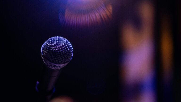 A microphone is spotlighted against a dark, blurred background, creating a dramatic atmosphere.