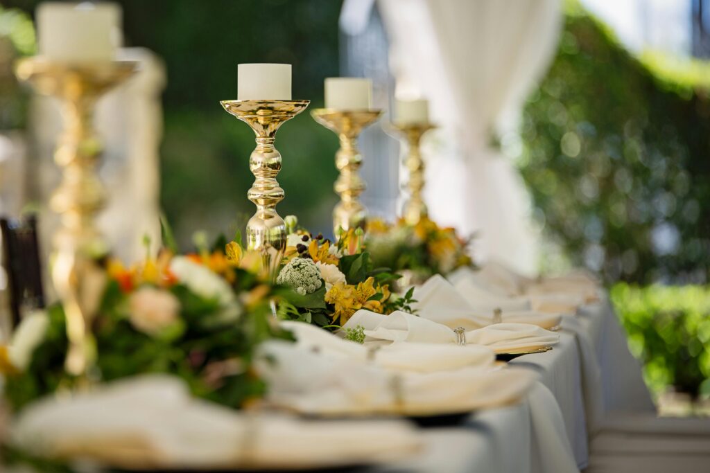 Luxurious outdoor wedding table decor with golden candlesticks and vibrant flower arrangements.